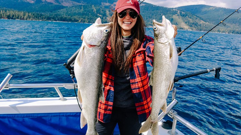 a person holding a fish on a boat in a body of water