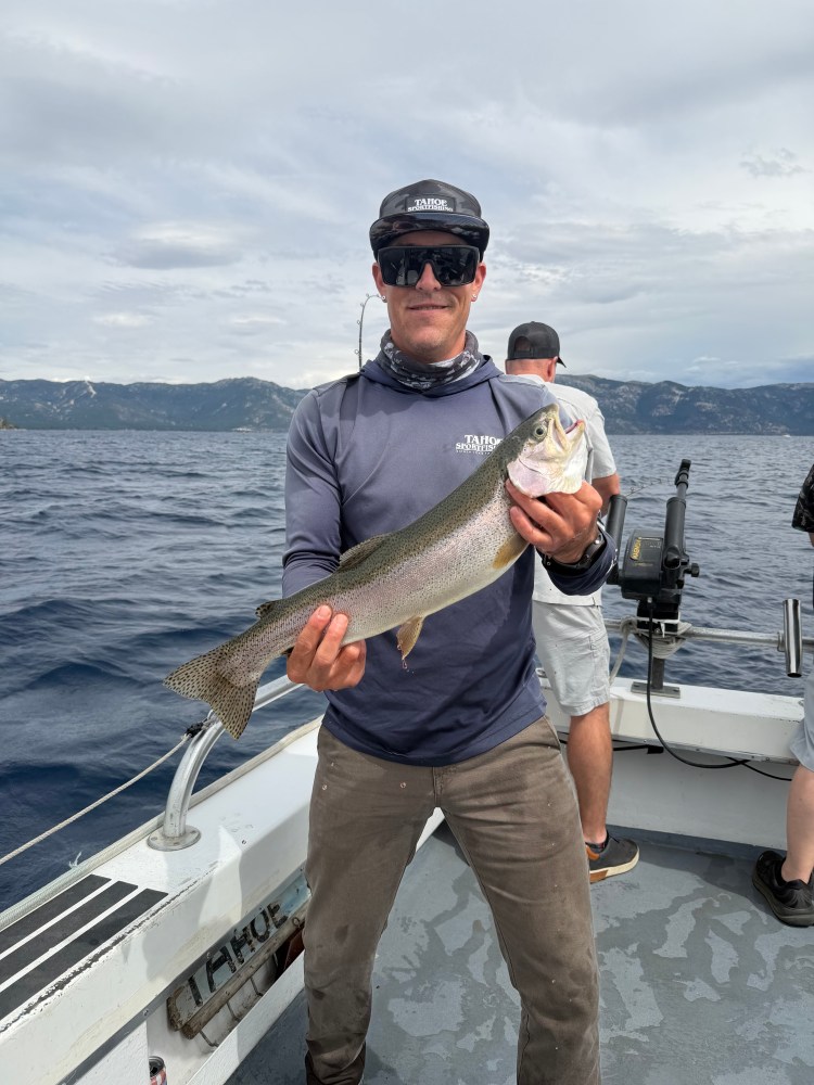 Man holding a fish on a boat in a lake.
